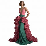 Woman wearing a pink and green gown with ruffled details on a gray background
