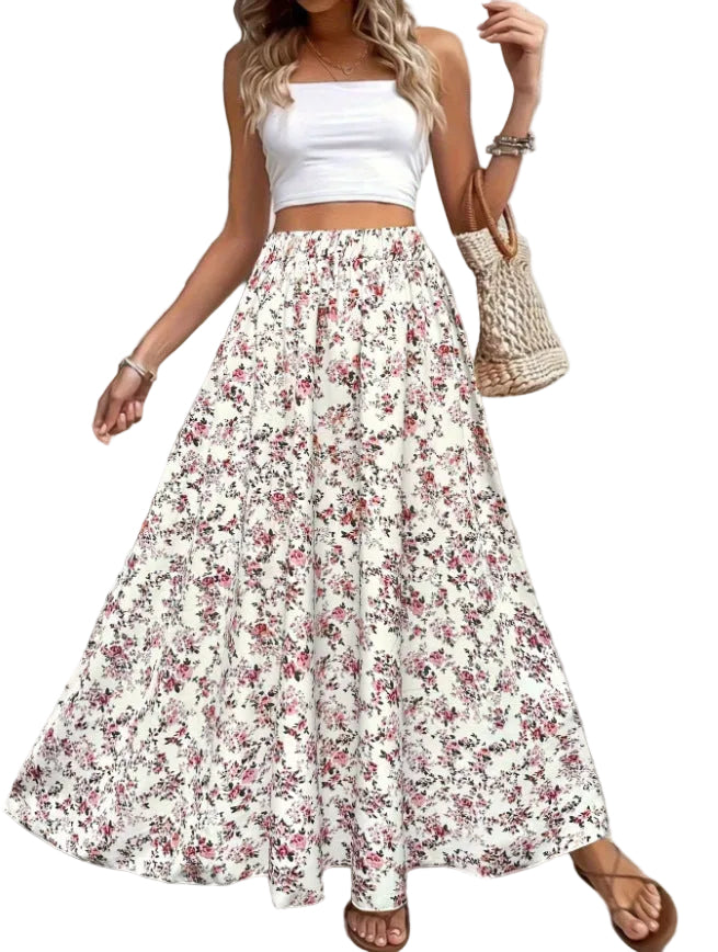 Woman wearing a white top and floral skirt with a plant and bag in the background