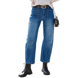 Person wearing blue jeans and black boots standing on a sidewalk.