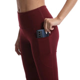 Maroon leggings with a pocket holding a phone on a white background