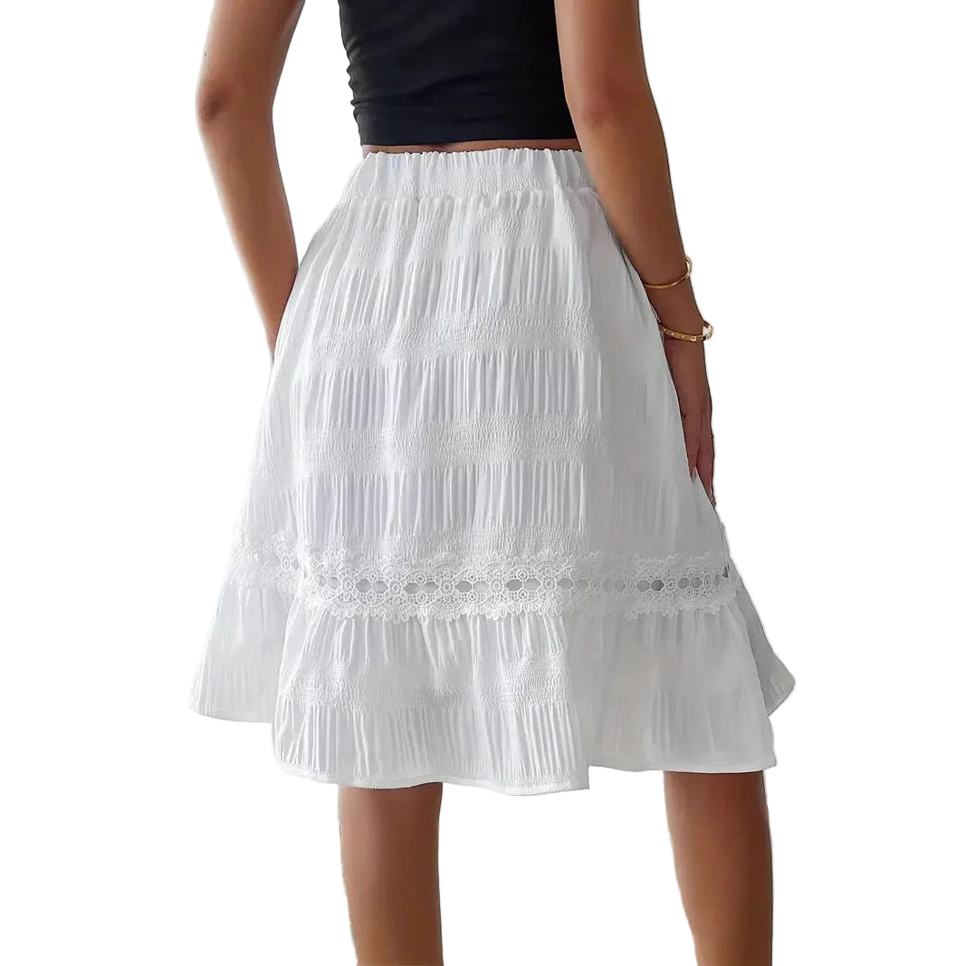 Person wearing a white skirt with lace details in a minimal indoor setting.