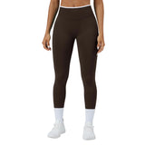 Person wearing brown leggings and white sneakers on a gray background