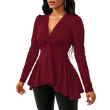 Woman wearing a burgundy long-sleeve top with a knot detail against a white background
