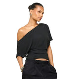 Woman wearing a black one-shoulder top and black pants on a white background