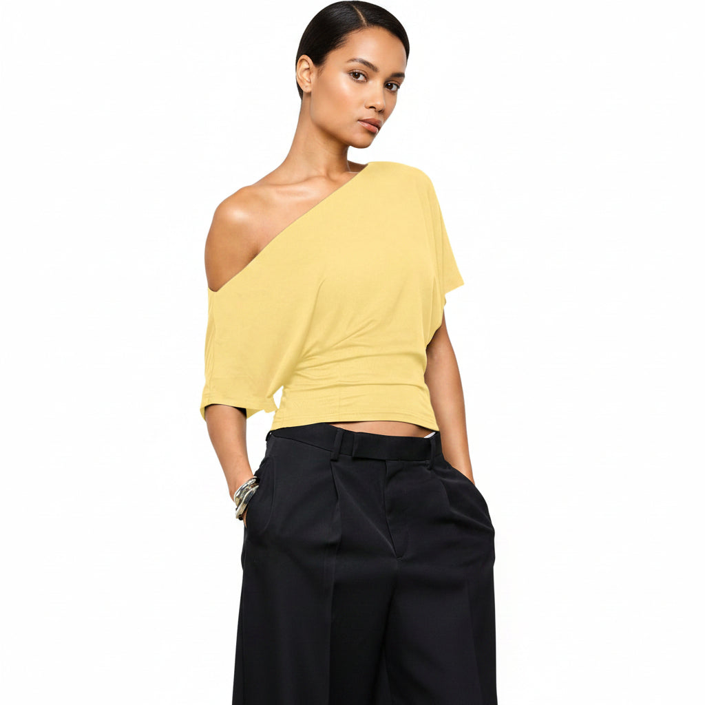 Yellow one-shoulder top worn by a person on a white background