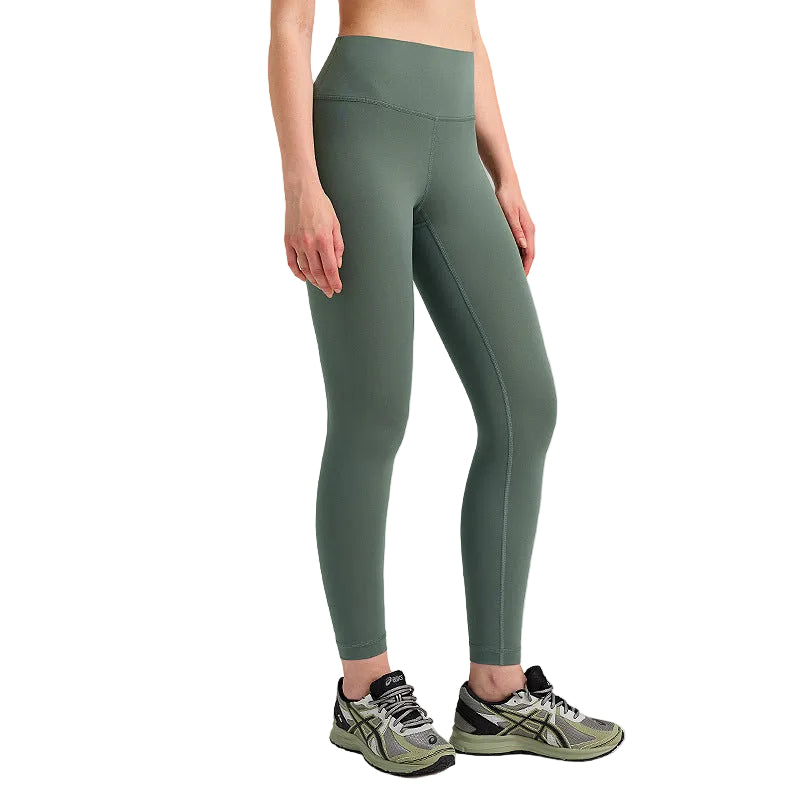 Person wearing green leggings and athletic shoes on a gray background