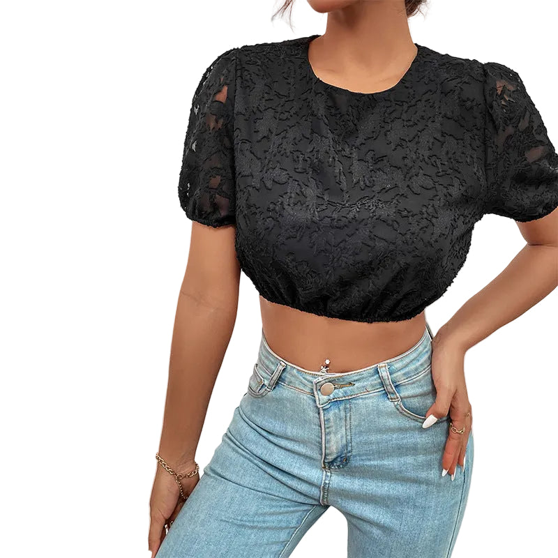 Person wearing a black lace top and blue jeans against a light gray background