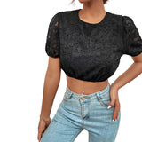 Person wearing a black lace top and blue jeans against a light gray background