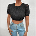 Person wearing a black lace top and blue jeans against a white background