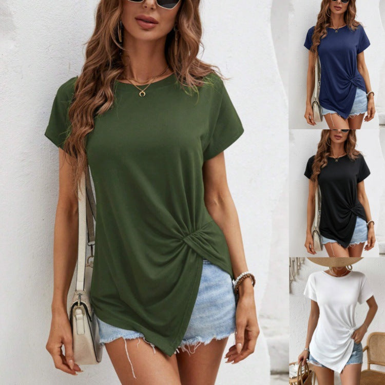 Woman wearing a green t-shirt with a knot detail and denim shorts against a white background.