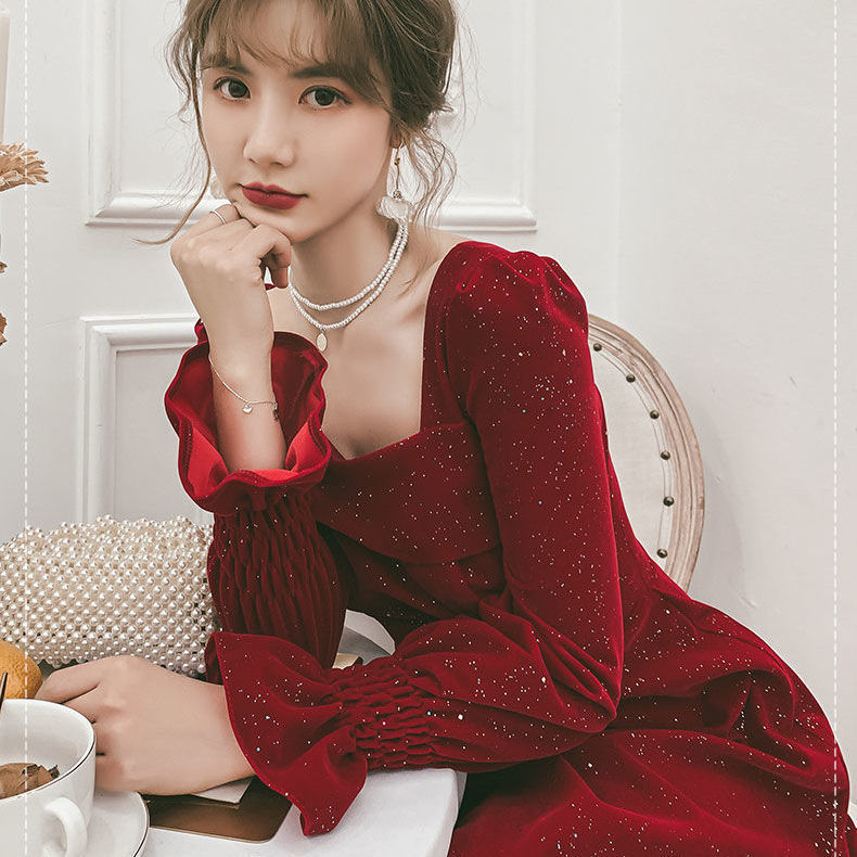 Woman in a red dress sitting at a table with a white background